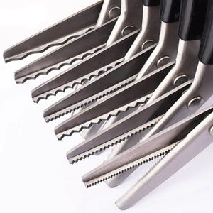 May include: A collection of stainless steel scissors with various blade patterns, including wavy, zigzag, and straight edges. The scissors have black handles and are arranged diagonally against a white background. Ideal for fabric and craft projects.