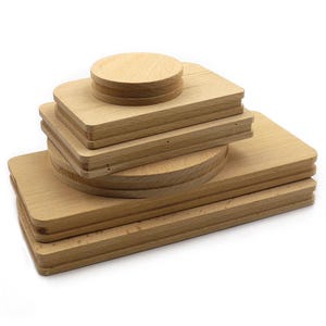 May include: A stack of unfinished wooden cutting boards and a round wooden lid. The boards are rectangular and circular, with a natural wood grain. The items are stacked on top of each other, creating a layered effect.
