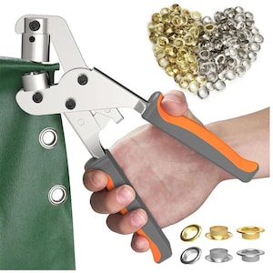 Op de afbeelding: Een zilveren metalen grommet tool met oranje en grijze handgrepen wordt gebruikt op een groene stof. Een verzameling gouden en zilveren grommets wordt in een hartvorm weergegeven. Verschillende grommets worden onderaan getoond.