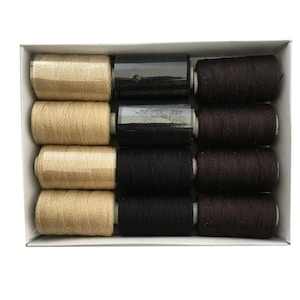 May include: A box of spools of thread in various colors. The spools are arranged in rows and columns. Colors include tan, black, and dark brown. The spools are cylindrical and appear to be made of cotton or a similar material. The box is white.