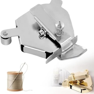 May include: A shiny, silver metal sewing machine binder attachment with a screw and a small spool of thread with a needle. The binder has a unique shape with a curved edge and a small roller. A gold-colored binder is also shown.
