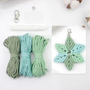 May include: A macrame craft kit featuring bundles of green and blue-green rope, a star-shaped macrame keychain, a metal clasp, a white marker, and a clear tag. The star keychain has a gradient of green and blue-green colors.