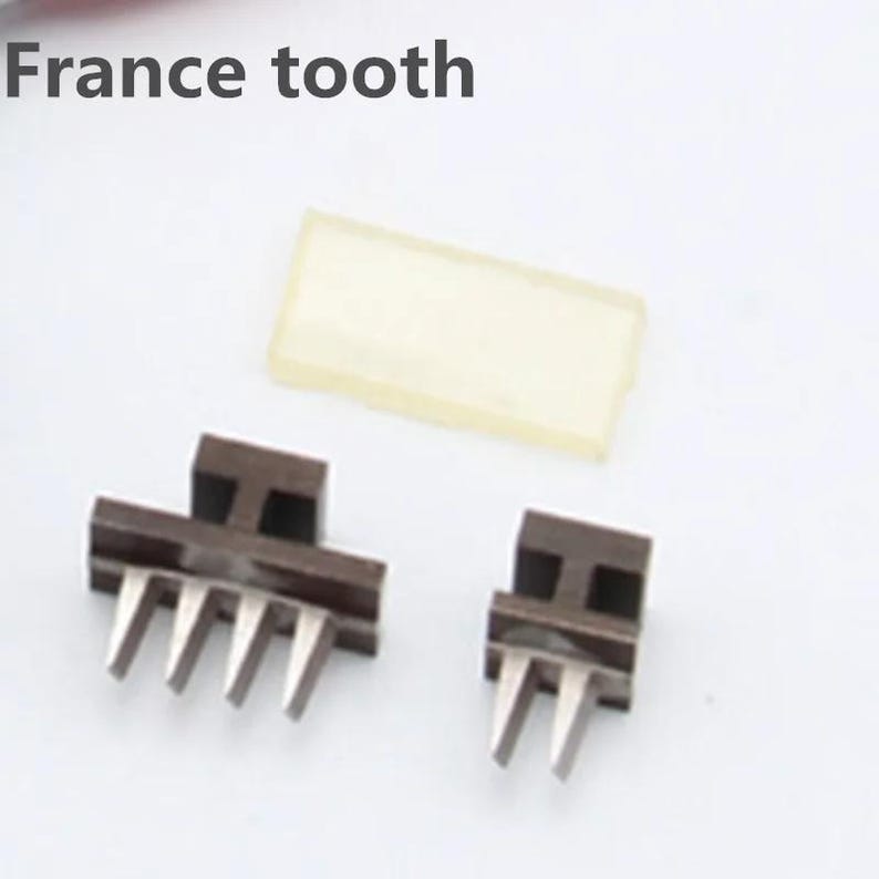 May include: Two brown metal pieces with multiple teeth, a clear plastic rectangle, and the text "France tooth".