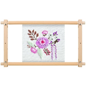 May include: A floral embroidery project in a wooden frame. The embroidery features a bouquet of flowers in shades of pink, purple, and white, with green leaves and brown accents. The wooden frame is light-colored and rectangular.
