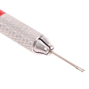 K&ouml;nnte beinhalten: Ein silbernes Uhrenarmbandwerkzeug mit rotem Griff. Das Werkzeug hat eine spitze Spitze mit zwei Zinken.