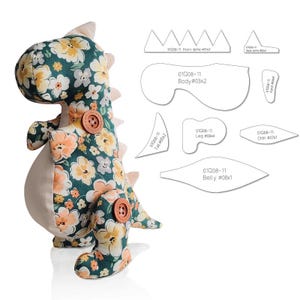 May include: A handmade stuffed dinosaur toy with a floral pattern in shades of green, yellow, and peach. The dinosaur has tan accents, wooden button details, and a pattern for the dinosaur's body parts.