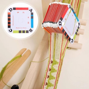 May include: A card weaving set with a wooden loom and colorful cards. The cards are red, black, green, and blue, with the text "card weaving" and "Made in China". The woven fabric has green, red, and white threads.