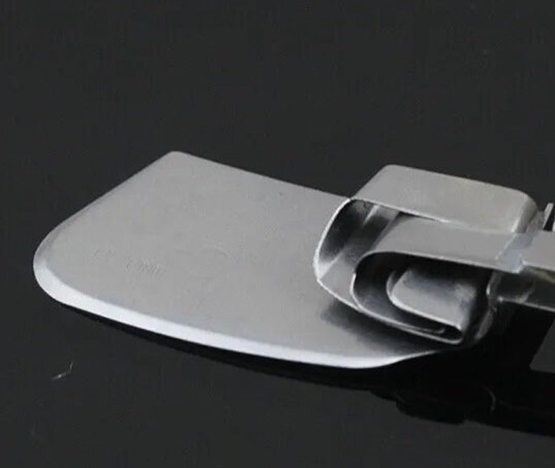 K&ouml;nnte beinhalten: Ein Teigschaber aus Edelstahl mit gebogener Klinge. Die Klinge ist rechteckig mit abgerundeter Kante. Der Griff besteht aus gefaltetem Metall. Das Werkzeug ist zum Backen und Kochen.