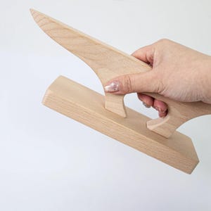 Può includere: Pressa per cuciture in legno chiaro con manico e estremità appuntita. Lo strumento è progettato per stirare le cuciture piatte nei progetti di cucito. L'impugnatura ha un design curvo per una presa comoda.