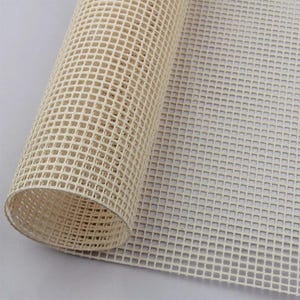 May include: A roll of white plastic canvas mesh, used for needlepoint and other crafts. The canvas is rolled up and the mesh is visible.