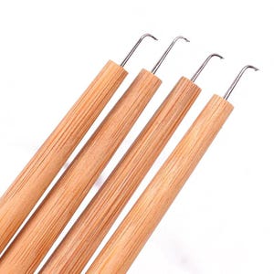 May include: Four craft tools with light brown bamboo handles and thin, silver-colored metal hooks at the tips. The tools are arranged diagonally, showing the cylindrical wooden shafts and the curved metal hooks used for precision work.