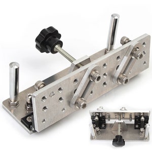 Peut inclure: Un outil en métal argenté avec un bouton noir et plusieurs trous. L'outil possède deux bras réglables qui peuvent être déplacés vers le haut et vers le bas. L'outil est utilisé pour plier le métal.