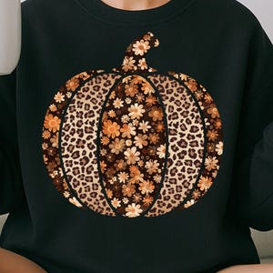 May include: Black sweatshirt with a pumpkin design. The pumpkin has a leopard print pattern and floral accents in brown and orange. The text "PNG - INSTANT DOWNLOAD" is at the bottom of the image.