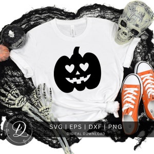 May include: A white t-shirt featuring a black pumpkin with heart eyes graphic. The text "SVG | EPS | DXF | PNG DIGITAL DOWNLOAD" is below the graphic.