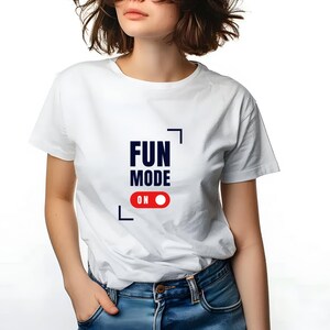 Puede incluir: Camiseta blanca con el texto "FUN MODE ON" en letras negras y rojas. El texto está enmarcado por un cuadrado negro.