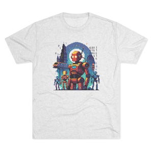 May include: A light grey t-shirt with a pixelated graphic of robots in a city. The central robot is orange with a red chest, and there are smaller robots in blue and yellow. A train and binary code are also visible.