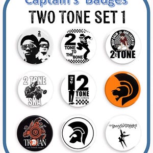 Op de afbeelding: Een set van negen Two Tone-badges met verschillende ontwerpen. De badges bevatten tekst en afbeeldingen, waaronder de woorden "Captain's Badges", "TWO TONE SET 1", "2 Tone", "Ska" en "Trojan". Het kleurenschema is voornamelijk zwart, wit en oranje.