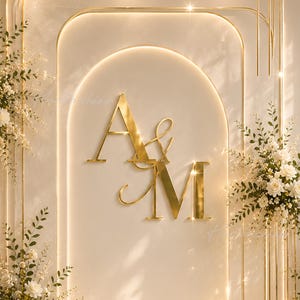 May include: A cream-coloured wedding backdrop with gold detailing. The design features the gold letters "A & M", floral arrangements of white roses, and vertical gold lines. Lit candles create a romantic atmosphere.