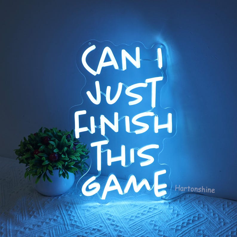 Puede incluir: Un letrero de ne&oacute;n blanco con el texto "Can I just finish this game" sobre un fondo azul.