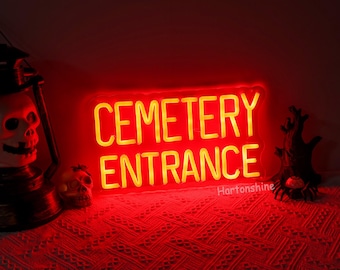 Op de afbeelding: Een rood neonbord met gele letters waarop "CEMETERY ENTRANCE" staat. Het bord is verlicht en werpt een rode gloed op de omgeving.