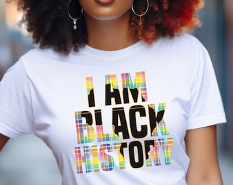 May include: A white t-shirt with the text "I AM BLACK HISTORY" printed in black letters. The letters are outlined in yellow and filled with a colorful plaid pattern.