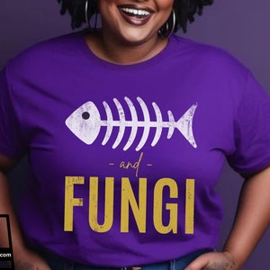 May include: Purple t-shirt with a white fish skeleton graphic and the text "and FUNGI" in yellow.