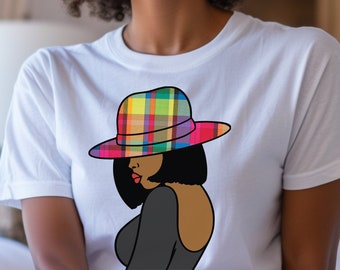 May include: White t-shirt featuring a graphic of a woman wearing a colorful plaid hat. The illustration depicts the woman with black hair and a black dress. The shirt has a round neck and short sleeves. The image includes the text "Color: White".