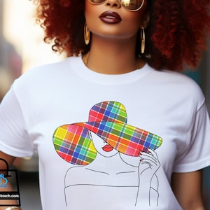 Puede incluir: Una camiseta blanca con un diseño de sombrero de cuadros de colores. El sombrero cubre los ojos de una mujer en un dibujo de línea. El texto "Color: White" está en la esquina superior izquierda de la imagen.