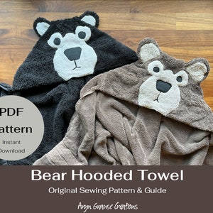 Op de afbeelding: Twee badhanddoeken met capuchon, een zwarte en een bruine, met berenkopjes op de capuchons. De handdoeken zijn gevouwen en liggen op een houten oppervlak. De tekst "PDF Pattern" staat in een cirkel aan de linkerkant van de afbeelding. De tekst "Instant Download" staat onder de cirkel. De tekst "Bear Hooded Towel" staat in grote letters onder de handdoeken. De tekst "Original Sewing Pattern & Guide" staat onder de naam van de handdoek. De tekst "Aryn Grause Creations" staat onderaan de afbeelding.