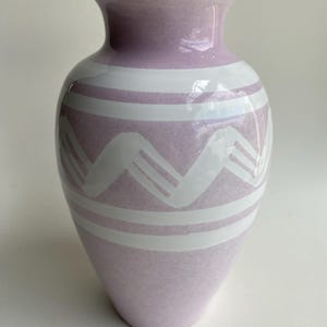 May include: A light purple ceramic vase with a white geometric pattern. The vase has a rounded base and a flared opening.