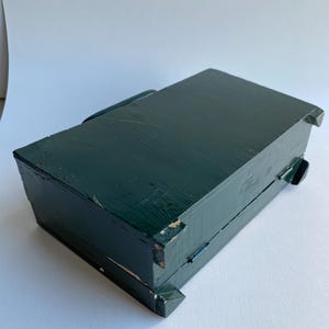 May include: A dark green wooden box with a hinged lid. The box has a simple design and is made of solid wood.