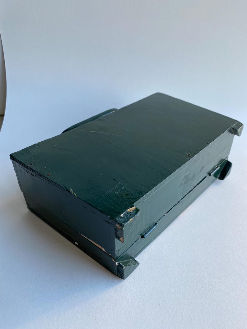 May include: A dark green wooden box with a hinged lid. The box has a simple design and is made of solid wood.