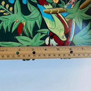 May include: A hand-painted wooden box with a colorful design of parrots and tropical plants. The box is approximately 8 inches long.