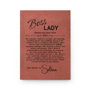 Puede incluir: Un diario de color marr&oacute;n rojizo con las palabras "Boss Lady" en una escritura elegante. El diario incluye una definici&oacute;n de "Boss Lady" y el nombre "Selina" en la parte inferior. El texto describe a una l&iacute;der que inspira a otros.
