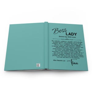 Puede incluir: Un diario de color turquesa con las palabras "Boss Lady" en una elegante escritura. La definici&oacute;n de "Boss Lady" est&aacute; impresa debajo, junto con una descripci&oacute;n de sus cualidades. El nombre "Tina" est&aacute; firmado en la parte inferior.