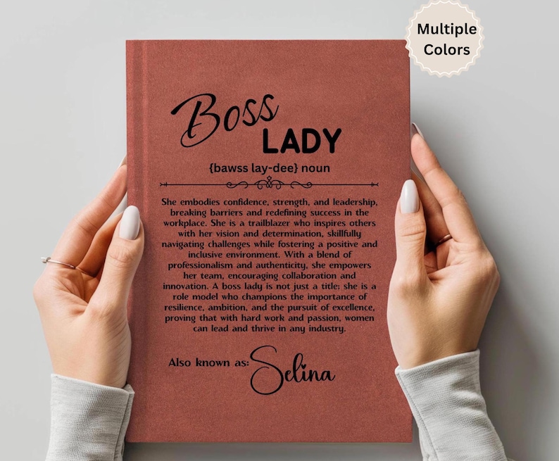 Puede incluir: Un cuaderno de color terracota sostenido por una persona. La portada presenta las palabras "Boss Lady" en una escritura elegante, junto con una definici&oacute;n y un texto inspirador. El cuaderno est&aacute; personalizado con el nombre "Selina".