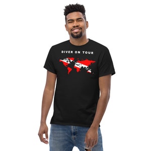 May include: A black t-shirt featuring a white graphic of a world map with a scuba diving flag overlay. The text "Diver on Tour" is printed in white above the map.