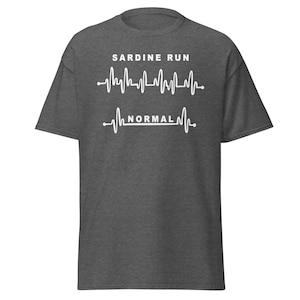 以下が含まれることがあります： 白いハートビートのグラフィックが描かれたダークヘザーグレーのTシャツ。ハートビートの上に「SARDINE RUN」、下に「NORMAL」の文字が書かれています。