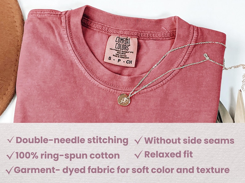May include: A close-up of a dusty rose coloured t-shirt with a tag that reads "Comfort Colors" and "S-P-CH". The t-shirt is made of 100% ring-spun cotton and features double-needle stitching, a relaxed fit, and garment-dyed fabric for a soft colour and texture.