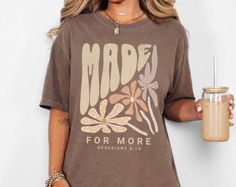 May include: A brown t-shirt with a graphic design of stylized flowers and the text "MADE FOR MORE EPHESIANS 2:10".