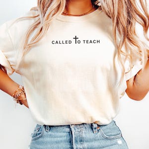 May include: A white t-shirt with the text "CALLED TO TEACH" and a cross symbol.