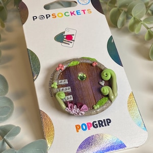 May include: A white ceramic mug with a black handle and the text "But First, Coffee" in a bold, black font. The mug is set against a blurred background, suggesting a cozy setting.