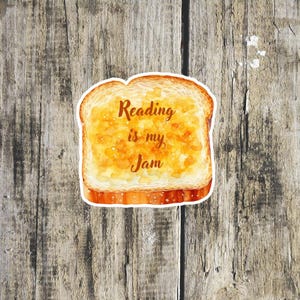 Könnte beinhalten: Ein Stück Toast mit einem gelben Belag und dem Text "Reading is my Jam" darauf.