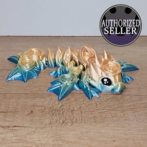 Könnte beinhalten: Eine 3D-gedruckte Figur eines Drachen mit einem Farbverlauf von Blau zu Gelb. Der Drache ist mit Rosen bedeckt und hat ein süßes, cartoonartiges Gesicht.