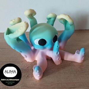 Könnte beinhalten: Eine farbenfrohe Oktopus-Figur mit einem Farbverlauf von Blau, Rosa und Gelb. Der Oktopus hat große, schwarze Augen und einen freundlichen Ausdruck.