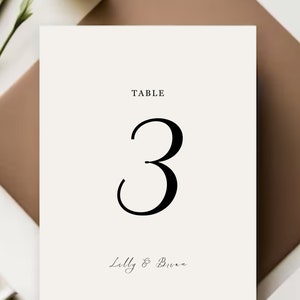 May include: White table number card with black text. The card reads "TABLE 3" and "Lilly & Brian".