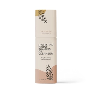 Puede incluir: Una botella blanca con una etiqueta marrón que dice "VEHAVEN Essentials" y "HYDRATING BOOST FOAMING OIL CLEANSER" con un diseño de hoja de palma. La botella es de 1,7 oz / 50 ml.