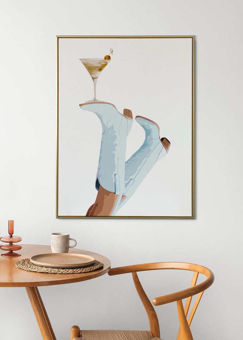 May include: A framed illustration of a pair of light blue cowboy boots with a martini glass resting on top. The martini glass has a green olive garnish.