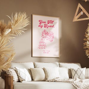 May include: A pink and white printable art print with the text "You fill my heart. To the brim." and a graphic of a cupid pouring from a bottle into a stack of glasses.