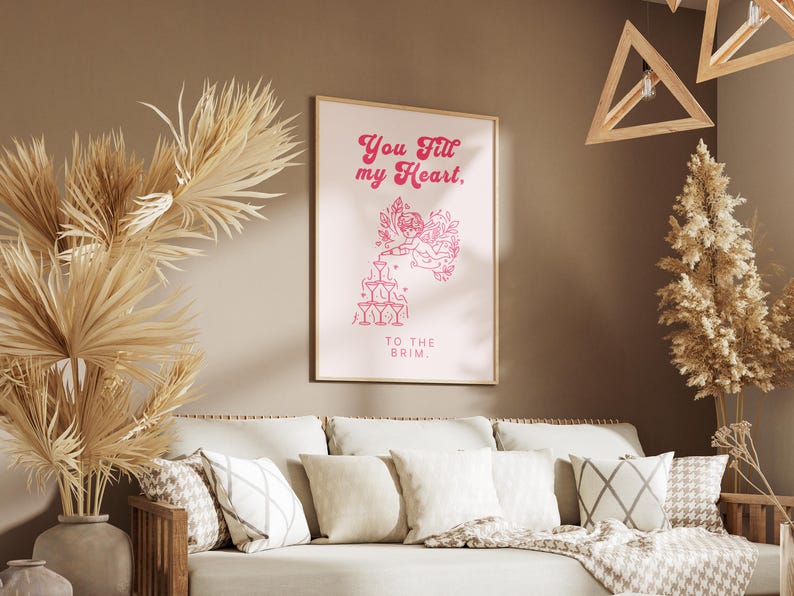 May include: A pink and white printable art print with the text "You fill my heart. To the brim." and a graphic of a cupid pouring from a bottle into a stack of glasses.